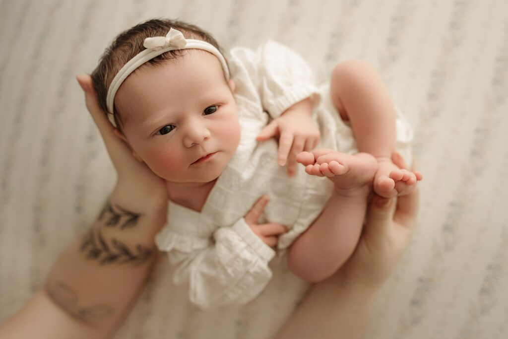 Parents cuddling their newborn baby during a professional newborn photography session