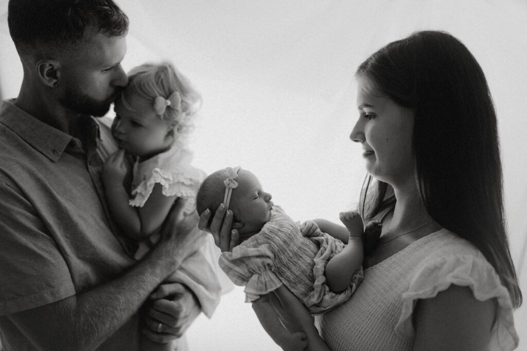 Parents cuddling their newborn baby during a professional newborn photography session